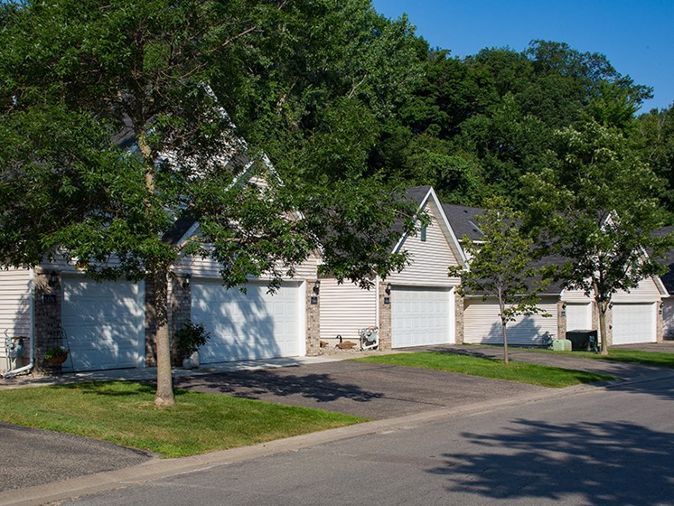 row of houses with garages and two large trees out front